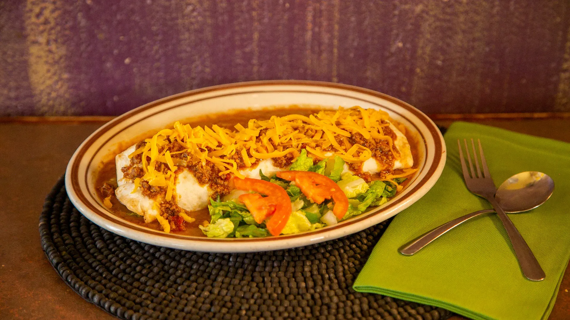 A smothered enchilada plate with red chile, melted cheese, lettuce, and tomato at Leal's Tamale Factory in Lubbock